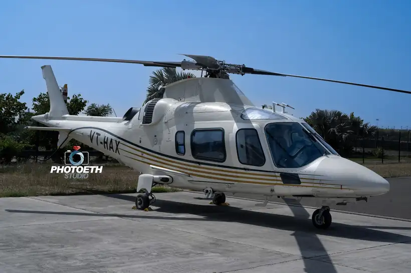A white twin-engine helicopter standing on a helipad against an evening sky