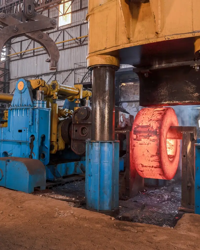 A forging press with a billet glowing orange between its dies