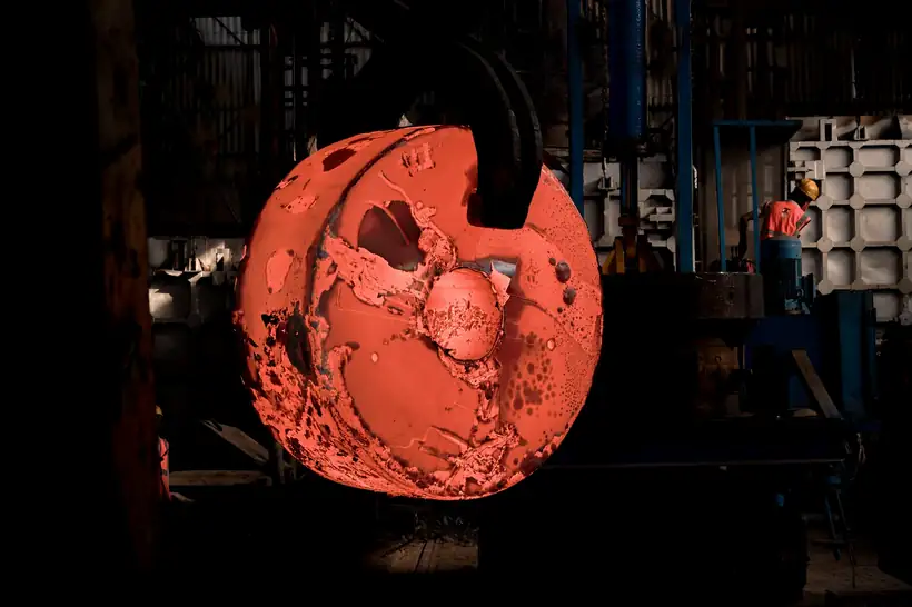 A forged ring glowing orange in the dark interior of a press