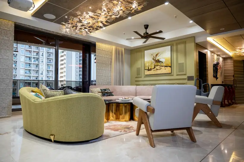 A living room with a chandelier, olive armchairs and a window looking on to towers