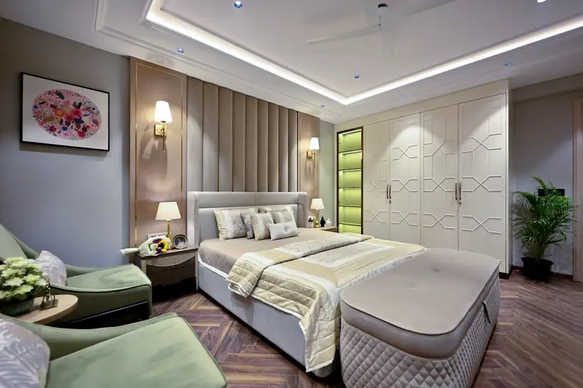 A hotel bedroom with an upholstered headboard, wall lights and a fitted wardrobe