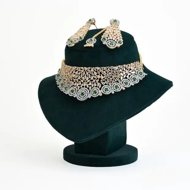 A necklace and earrings on a green velvet bust against white